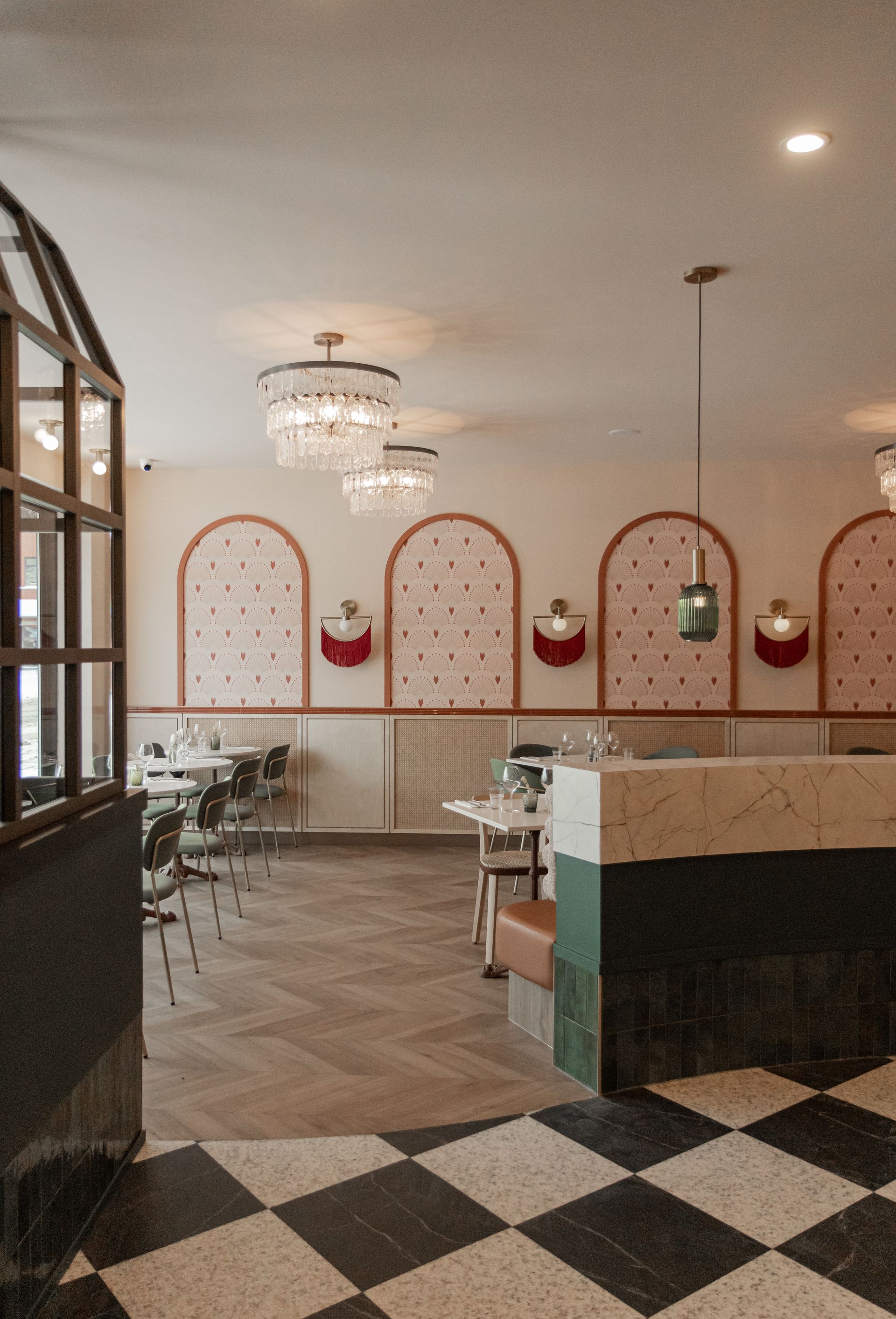 Intérieur de restaurant lumineux et élégant avec tables blanches, lustres, décoration murale en arc et sol à damier.