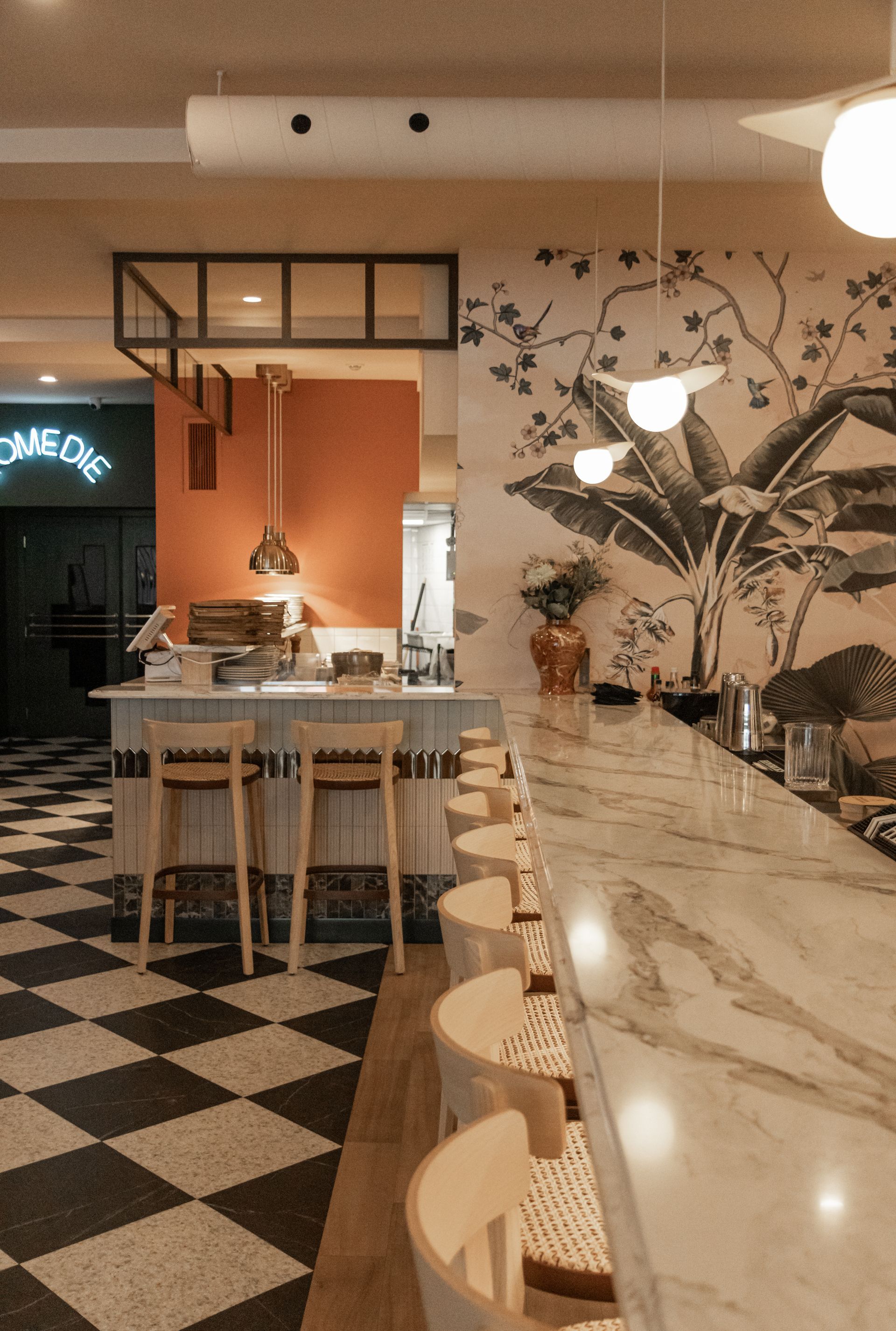 Intérieur de café élégant avec comptoir en marbre, sol à damier, tabourets de bar et fresque murale florale