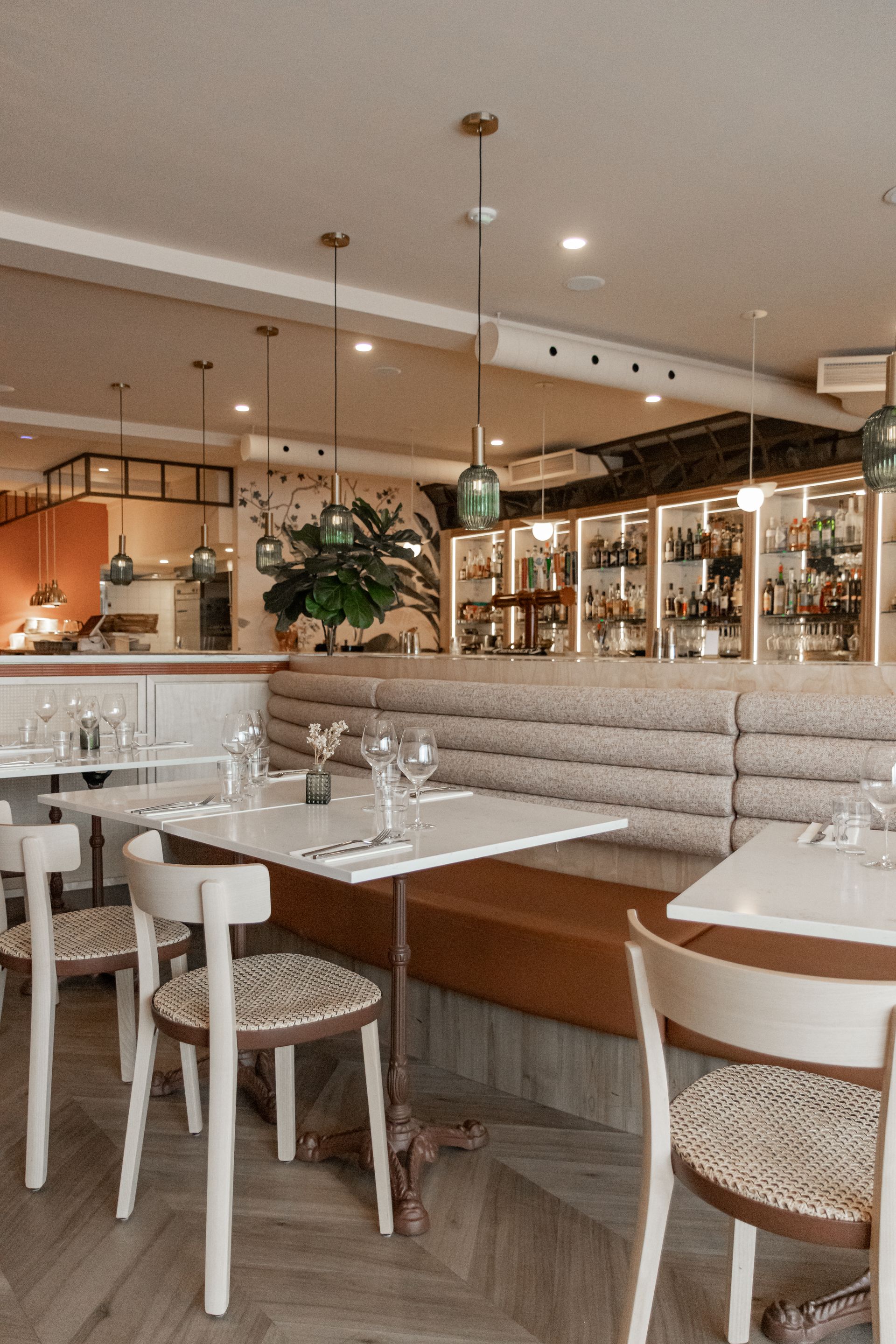 Intérieur de café moderne avec tables blanches, chaises en osier et éclairage suspendu chaleureux