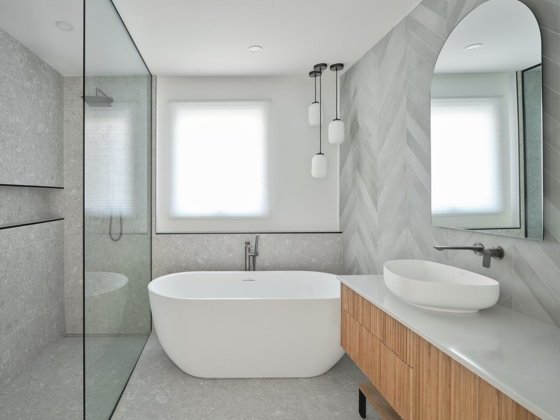 Salle de bains moderne avec baignoire, vasque et carrelage à chevrons.