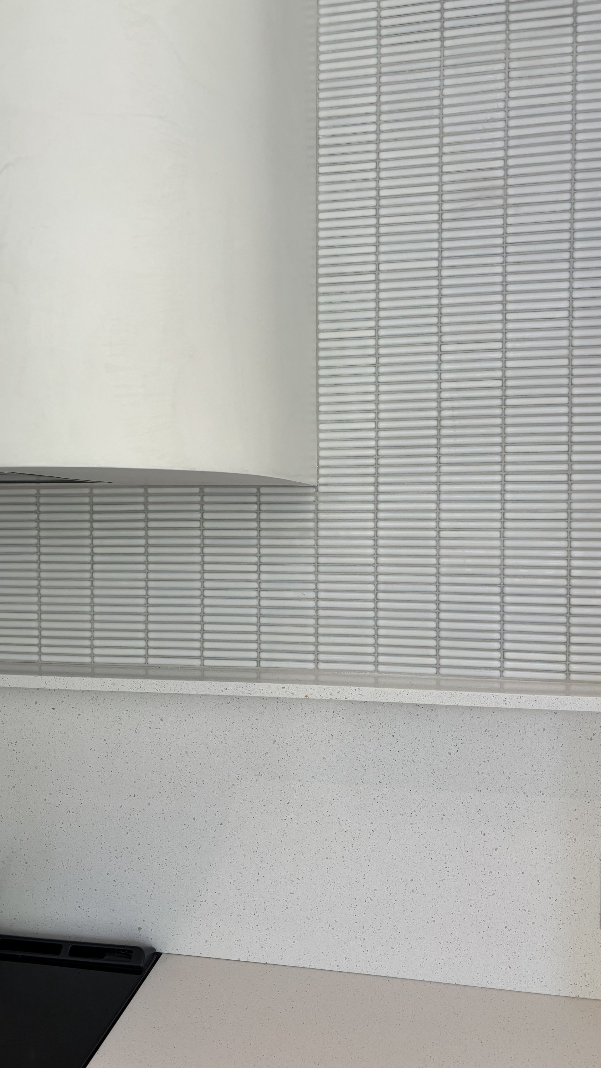 Mur blanc texturé avec une grande colonne cylindrique et des panneaux gris mouchetés en partie basse.