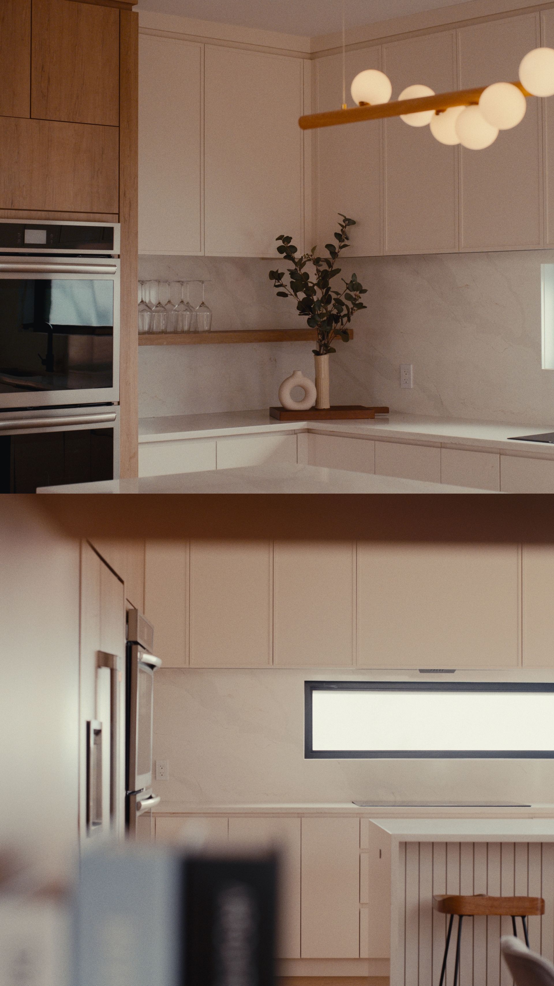 Cuisine moderne avec placards blancs, fours encastrés et luminaire à sphères.