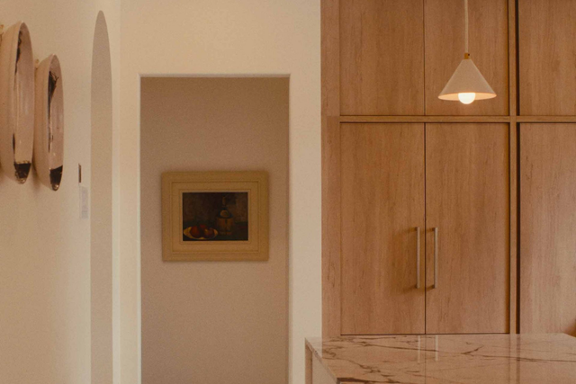 Minimalist hallway with wood cabinetry, a hanging pendant light, and framed wall art