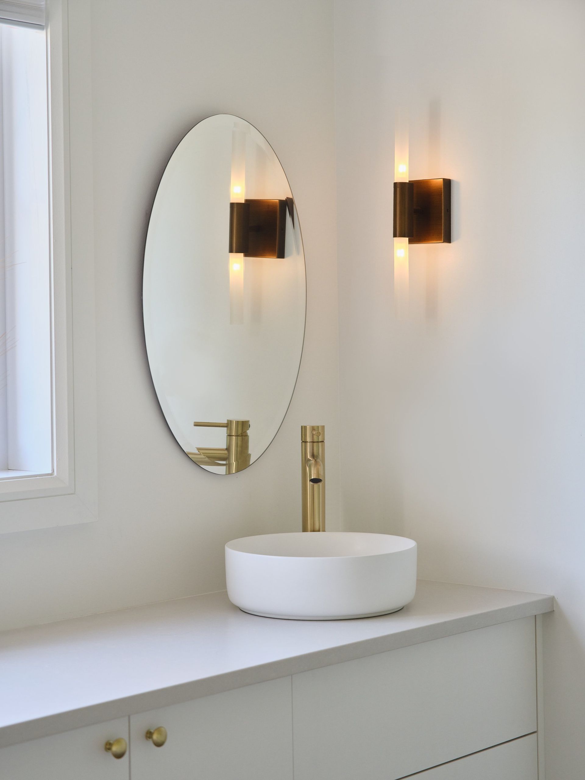 Une salle de bain avec un miroir rond et un lavabo