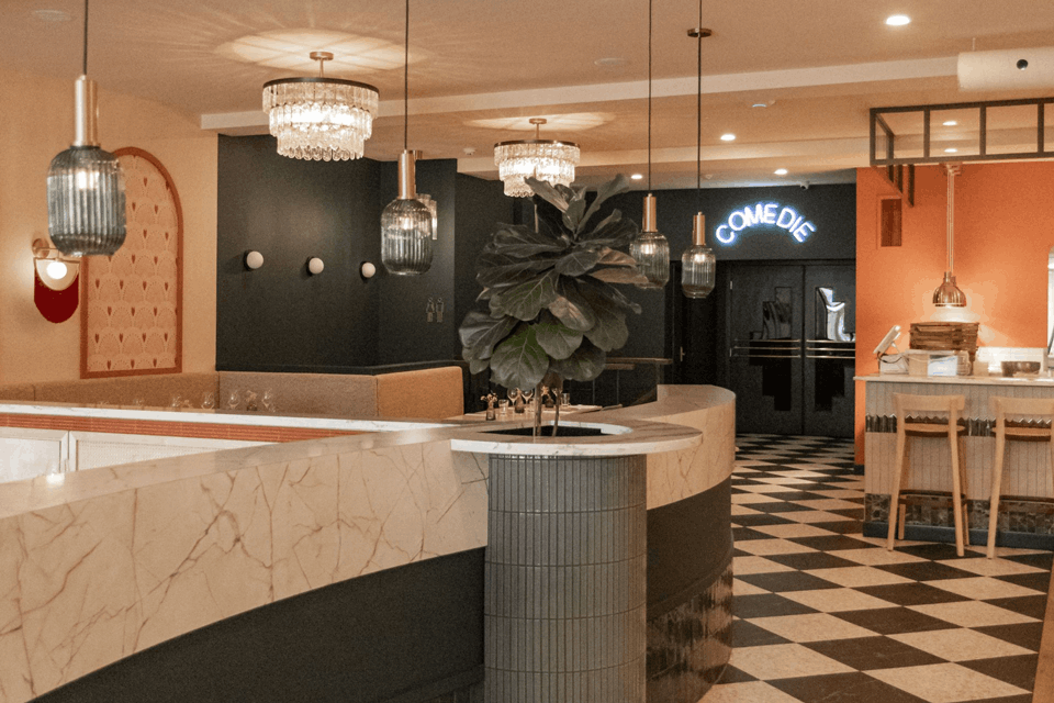 Intérieur de restaurant moderne avec comptoir en marbre, luminaires suspendus et sol à damier