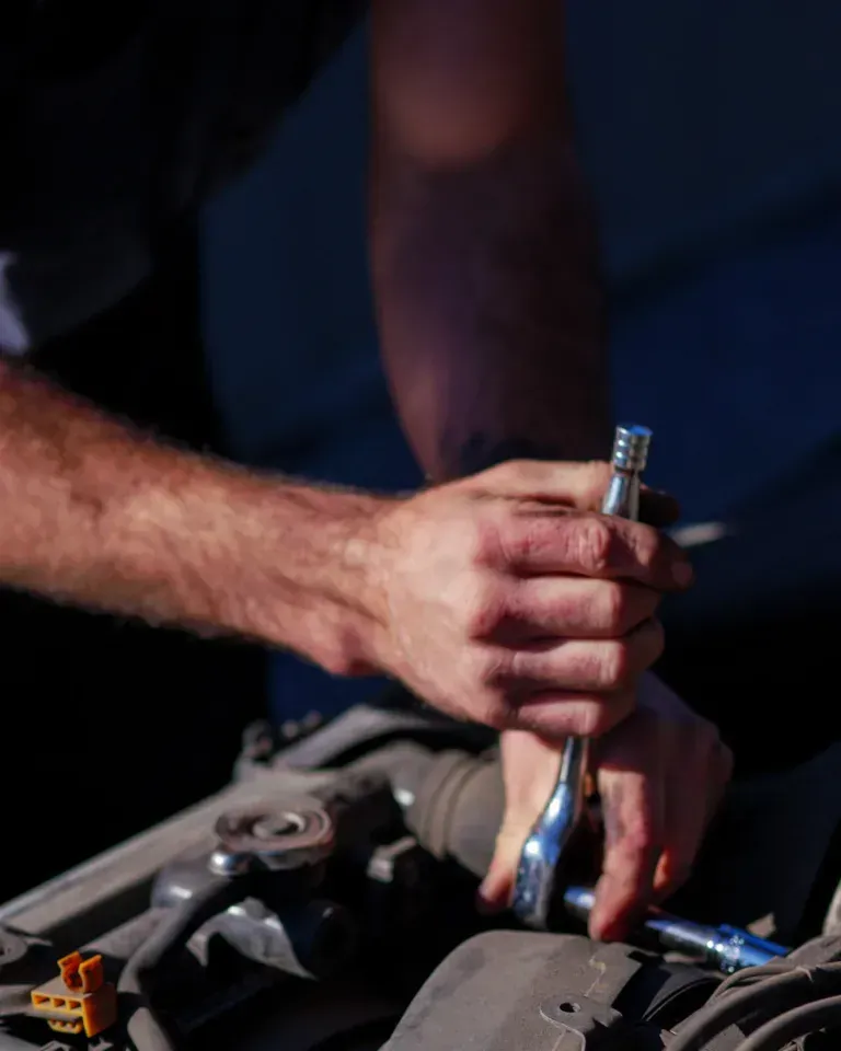 Person tightening a metal fitting with a wrench on a machine in a dimly lit workspace Person tightening a metal fitting with a wrench on a machine in a dimly lit workspace
