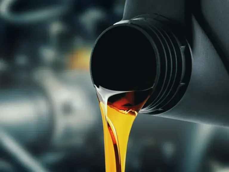 Motor oil pouring from a black container against a blurred background