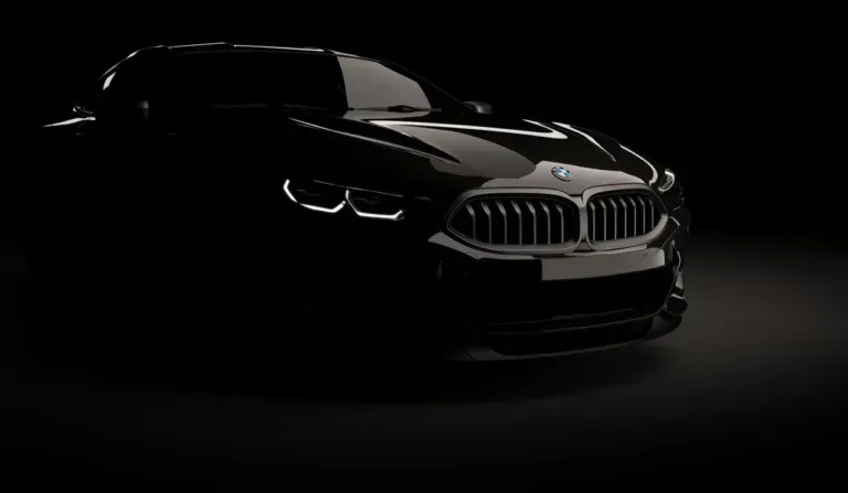 Black BMW sedan in a dark studio, front view with illuminated grille and headlights