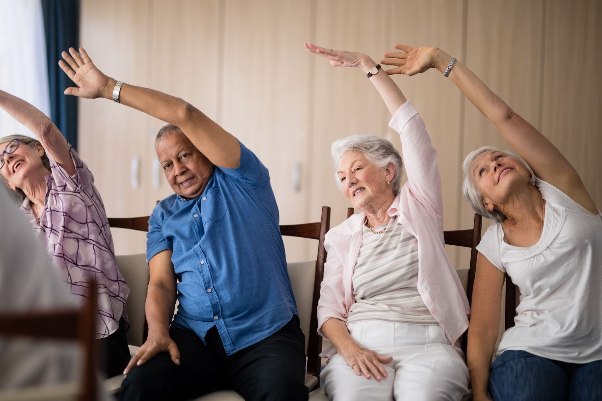 Group stretching in chairs during a gentle exercise class indoors