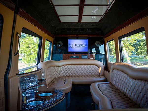 The inside of a limousine with a couch and a television.