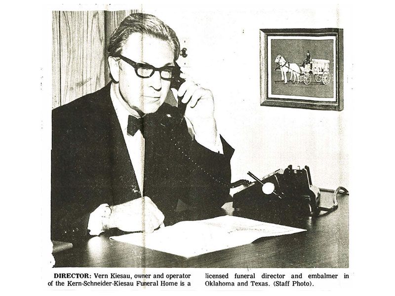 A black and white photo of a man talking on a phone