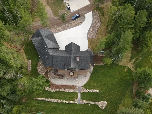 An aerial view of a house surrounded by trees and grass