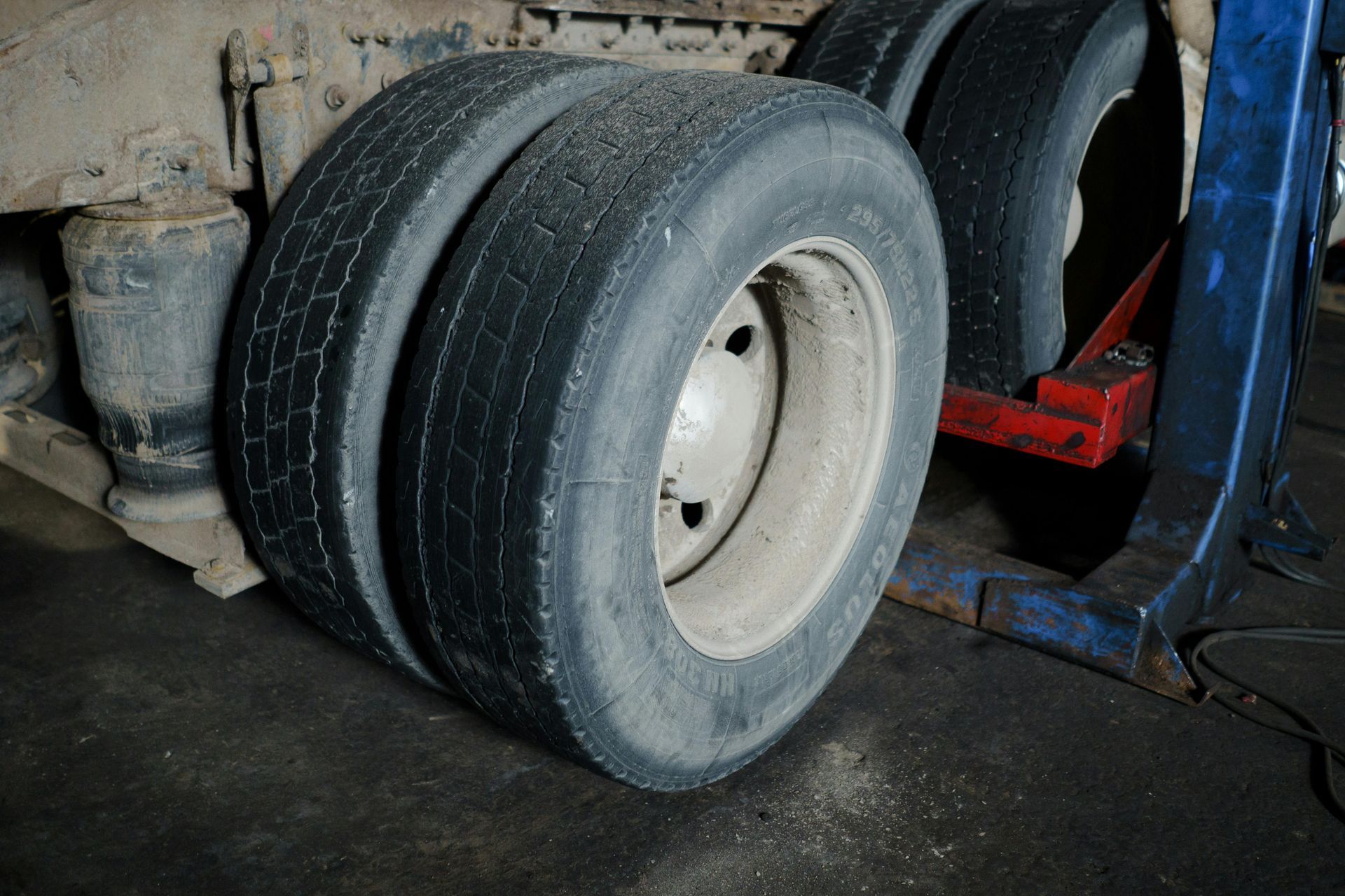 Close-up of a truck’s rear wheels on a lift in a garage, with tire tread visible.