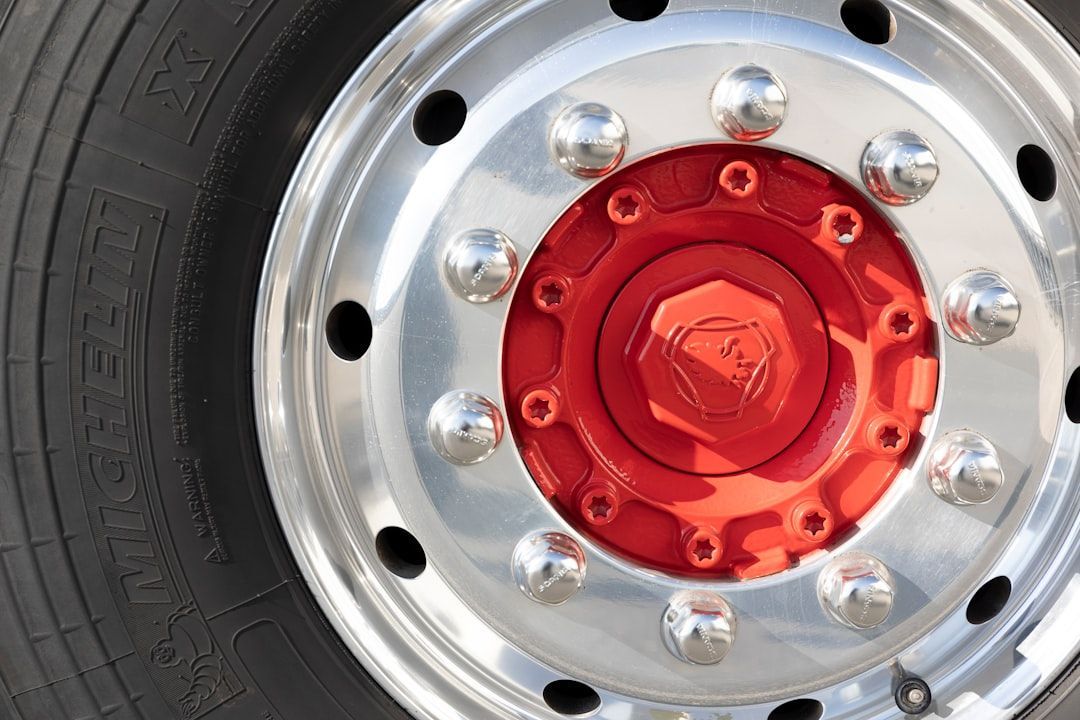 Close-up of a red and silver truck wheel rim with lug nuts and tire sidewall visible