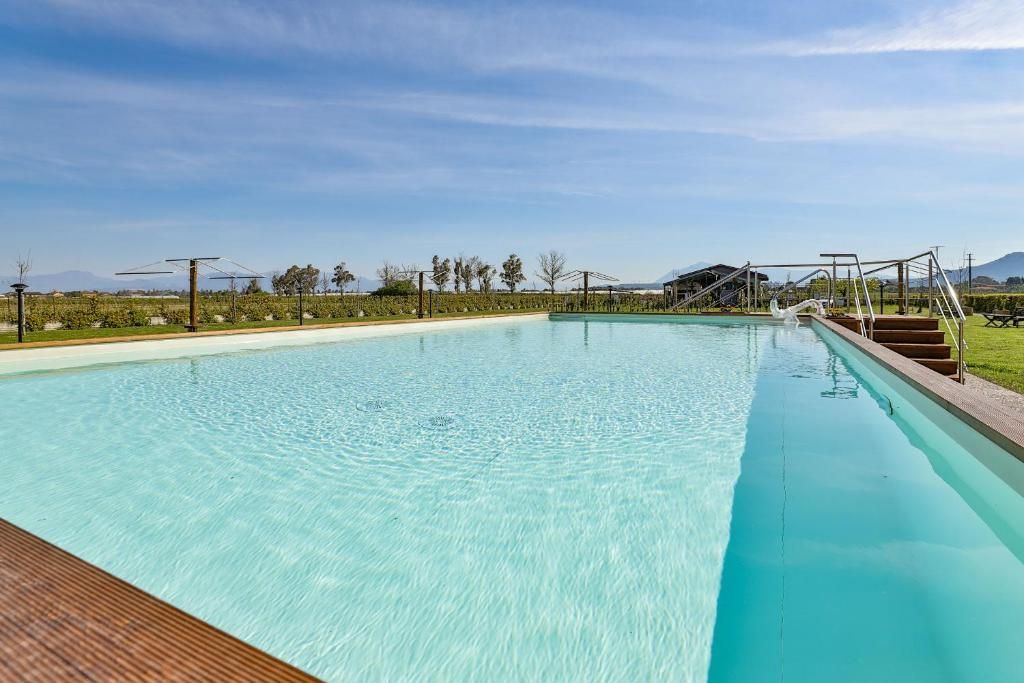 Una grande piscina è circondata da alberi e da un ponte in legno.