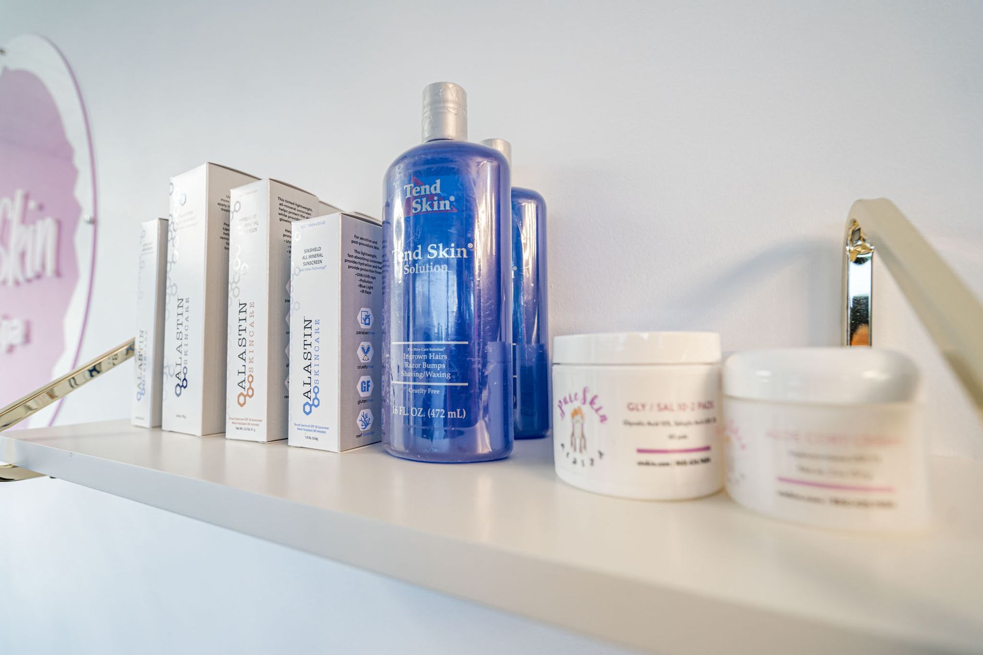Shelf with skincare products, including a blue bottle, white boxes, and cream jars on a white shelf