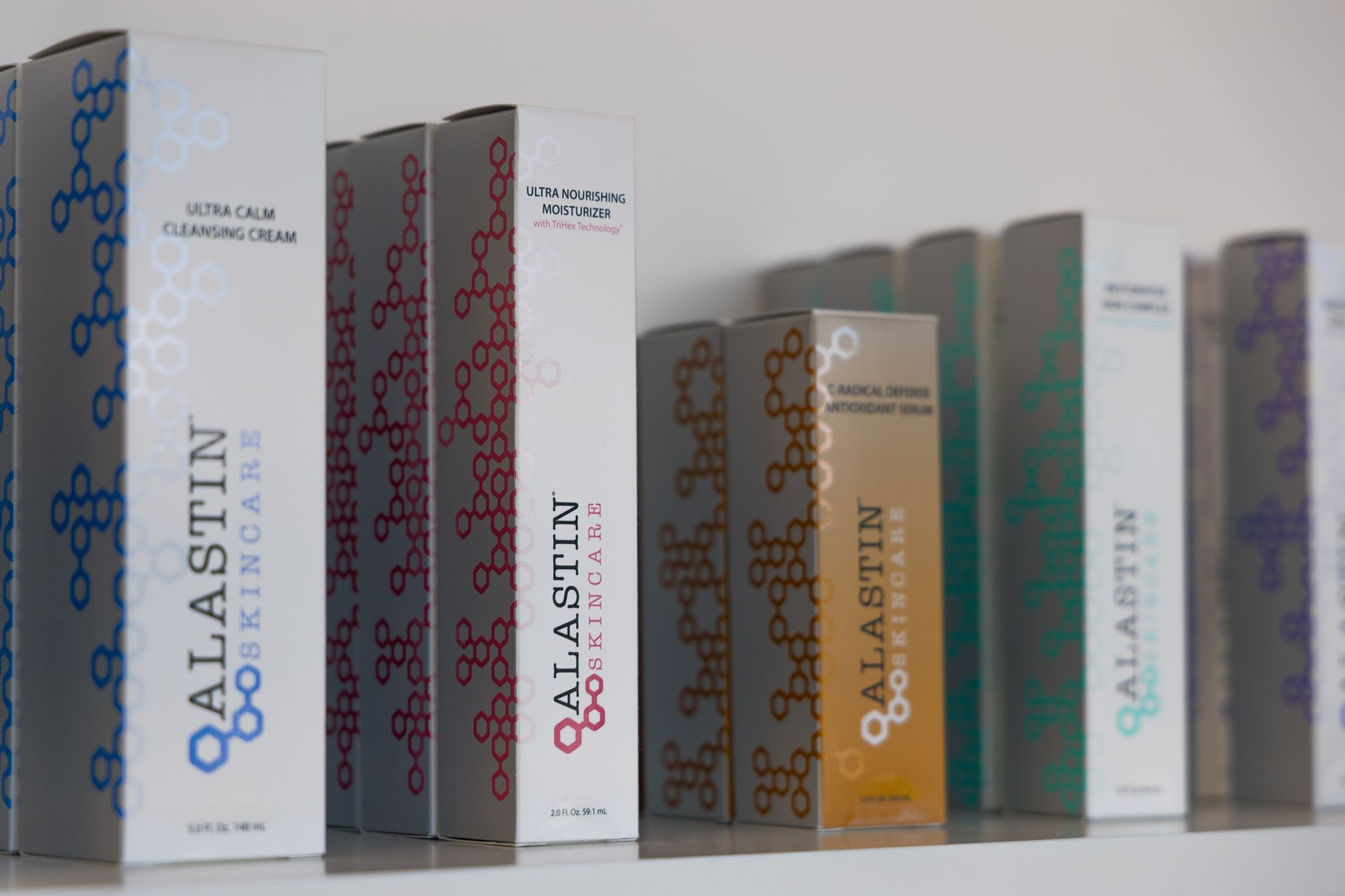 Several Qalastin perfume boxes lined up on a shelf in assorted colors.