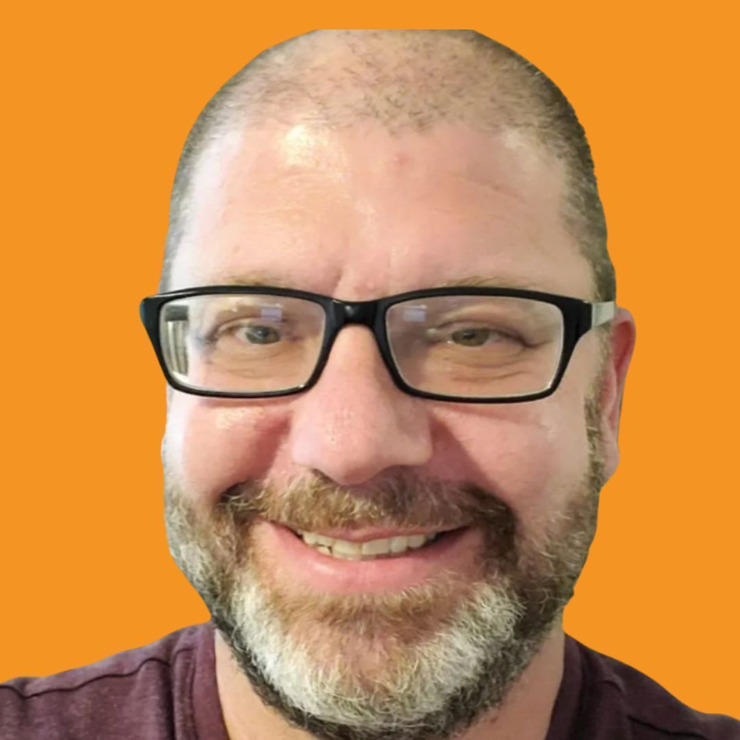 Smiling man with glasses and a beard against an orange background.