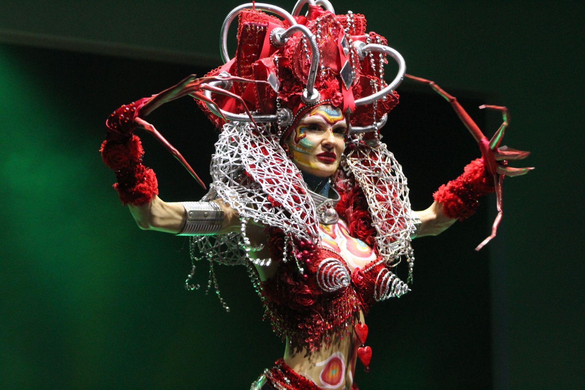 Woman in red lobster-themed costume with intricate headpiece and body paint, posed on stage.