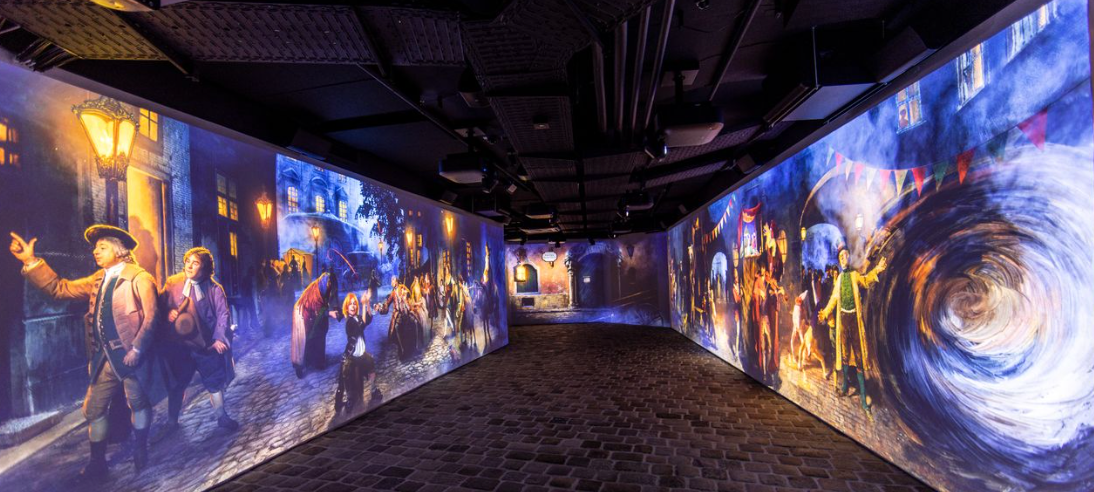 A narrow, dark hallway with projected artwork of a city scene on the walls.