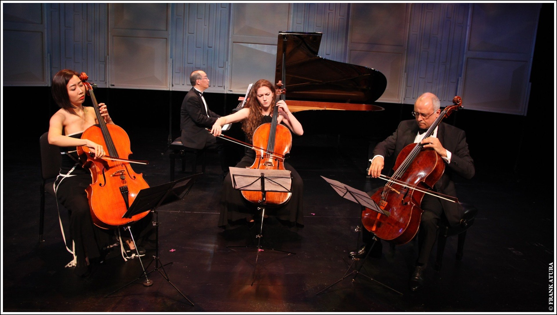A cello quartet performing on stage with a pianist, dressed formally.
