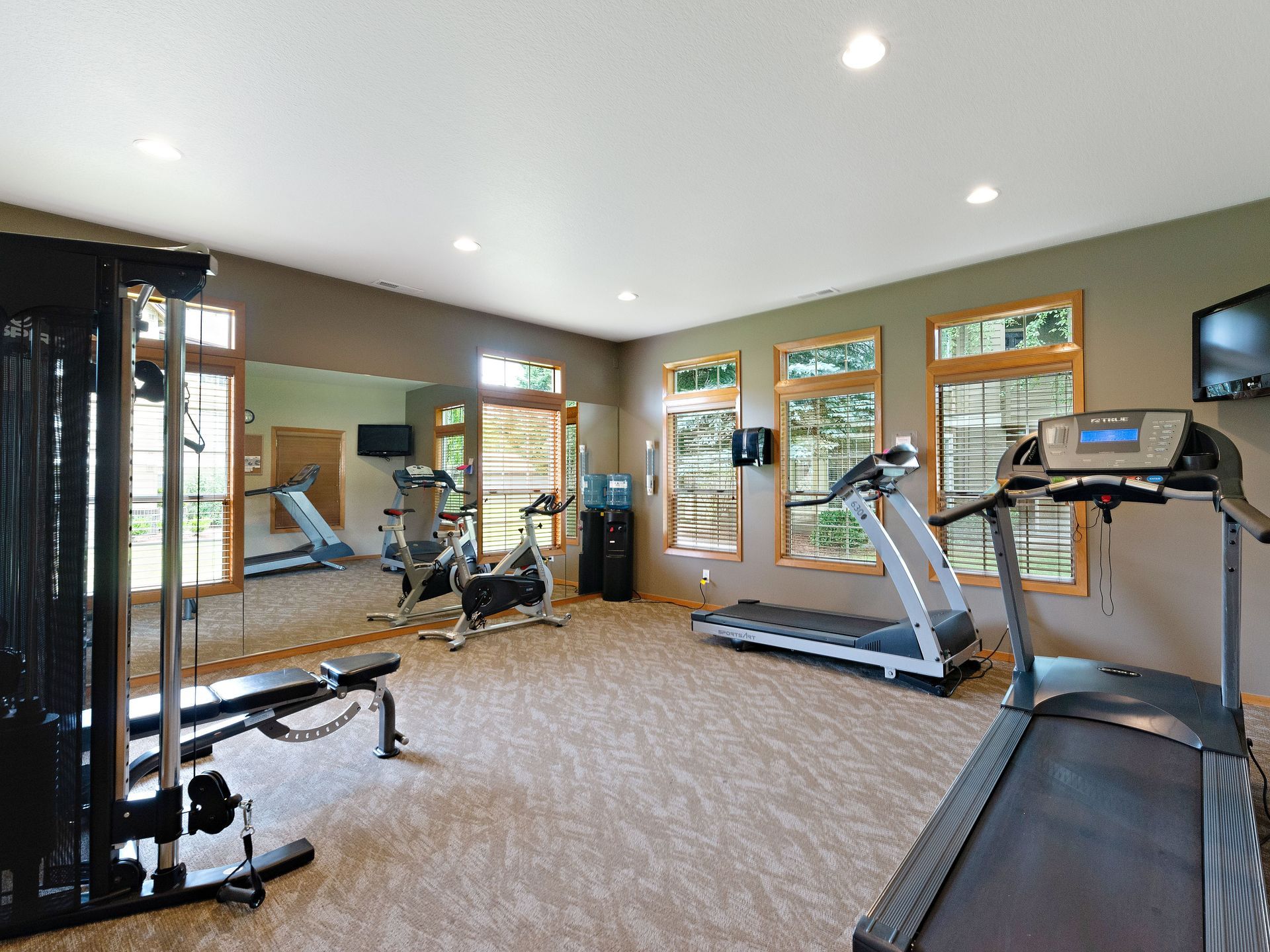 Home gym with treadmills, stationary bike, and mirrored wall in a carpeted room