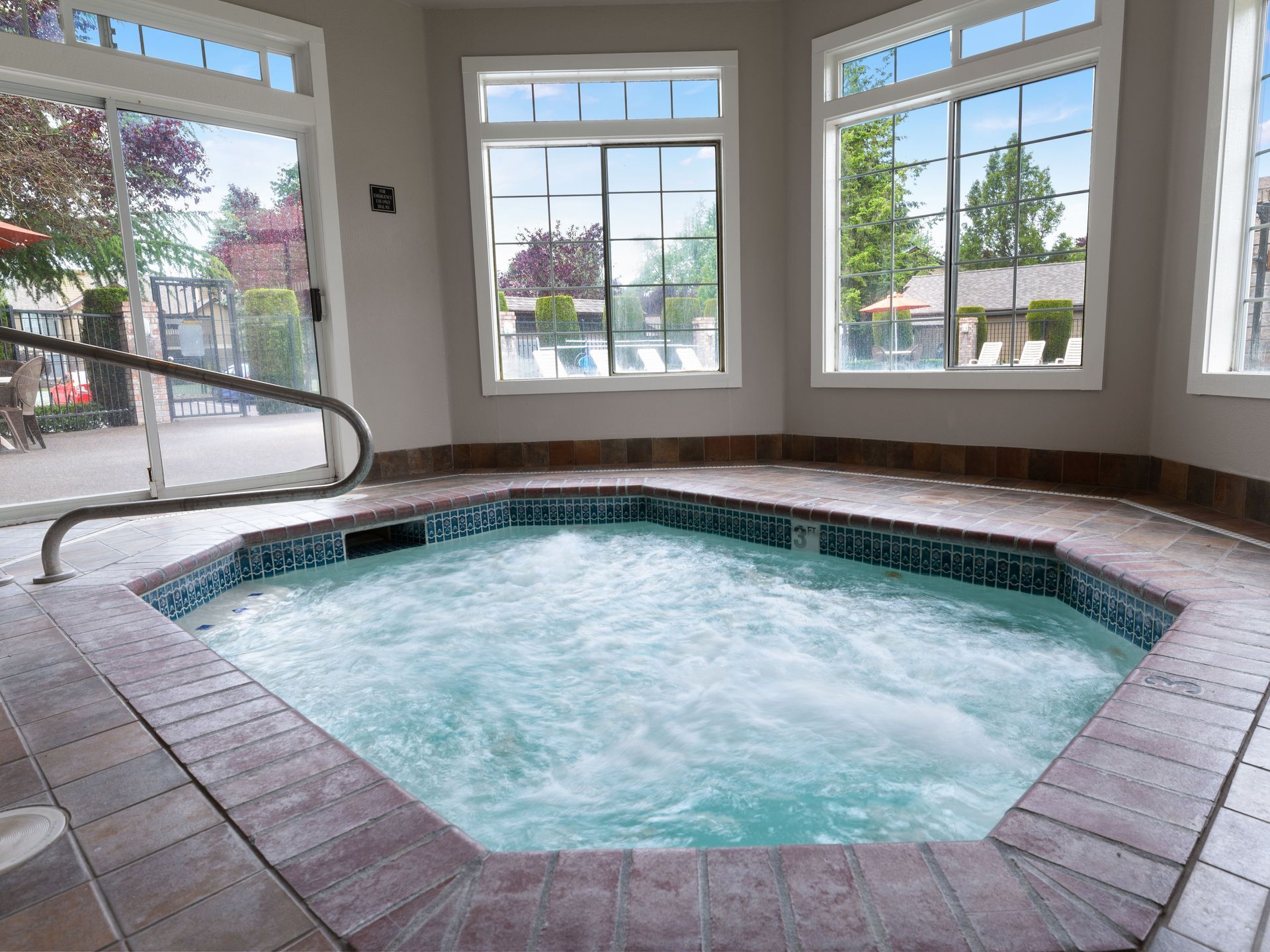 Indoor hot tub with bubbling water beside large windows overlooking a garden