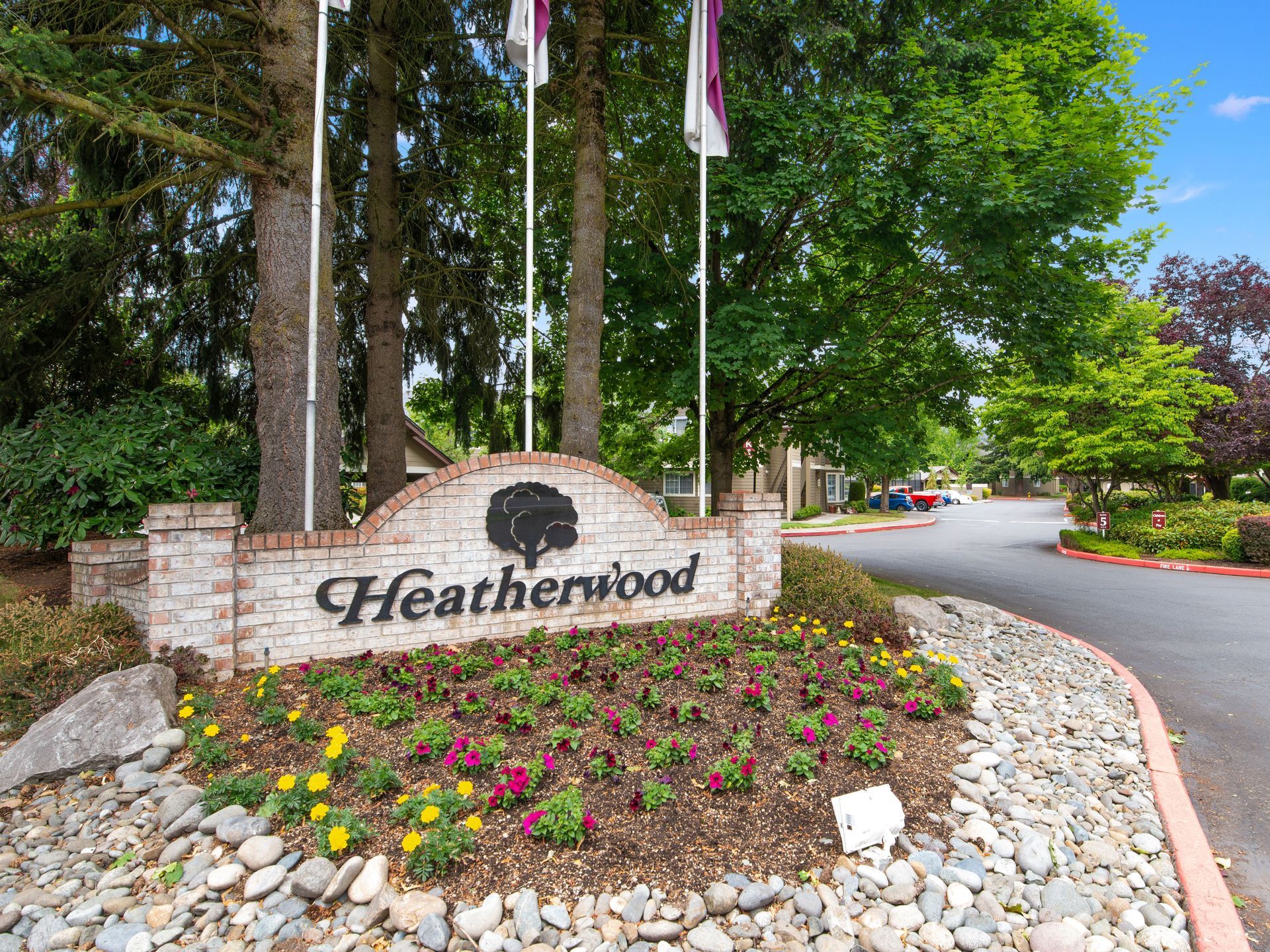 Heatherwood entrance sign beside a flower bed and tree-lined driveway