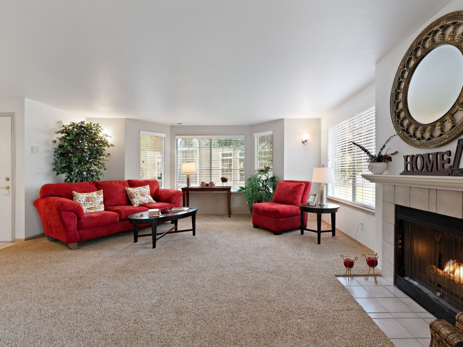 Bright living room with red sofas, bay window, fireplace, and coffee table