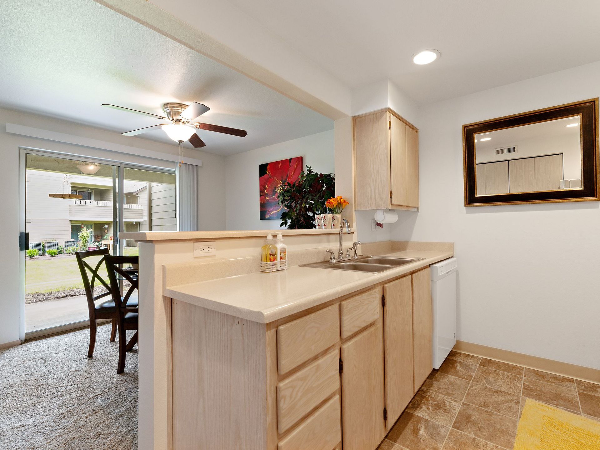 Bright kitchen with island, light wood cabinets, and a dining area by sliding glass doors