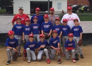 Youth baseball team posing together in red and blue uniforms on a field