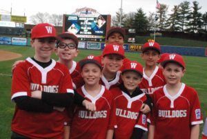 Youth baseball team in red Bulldogs uniforms posing on a field, smiling at the camera
