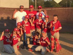Youth baseball team in red uniforms posing with coaches on a field