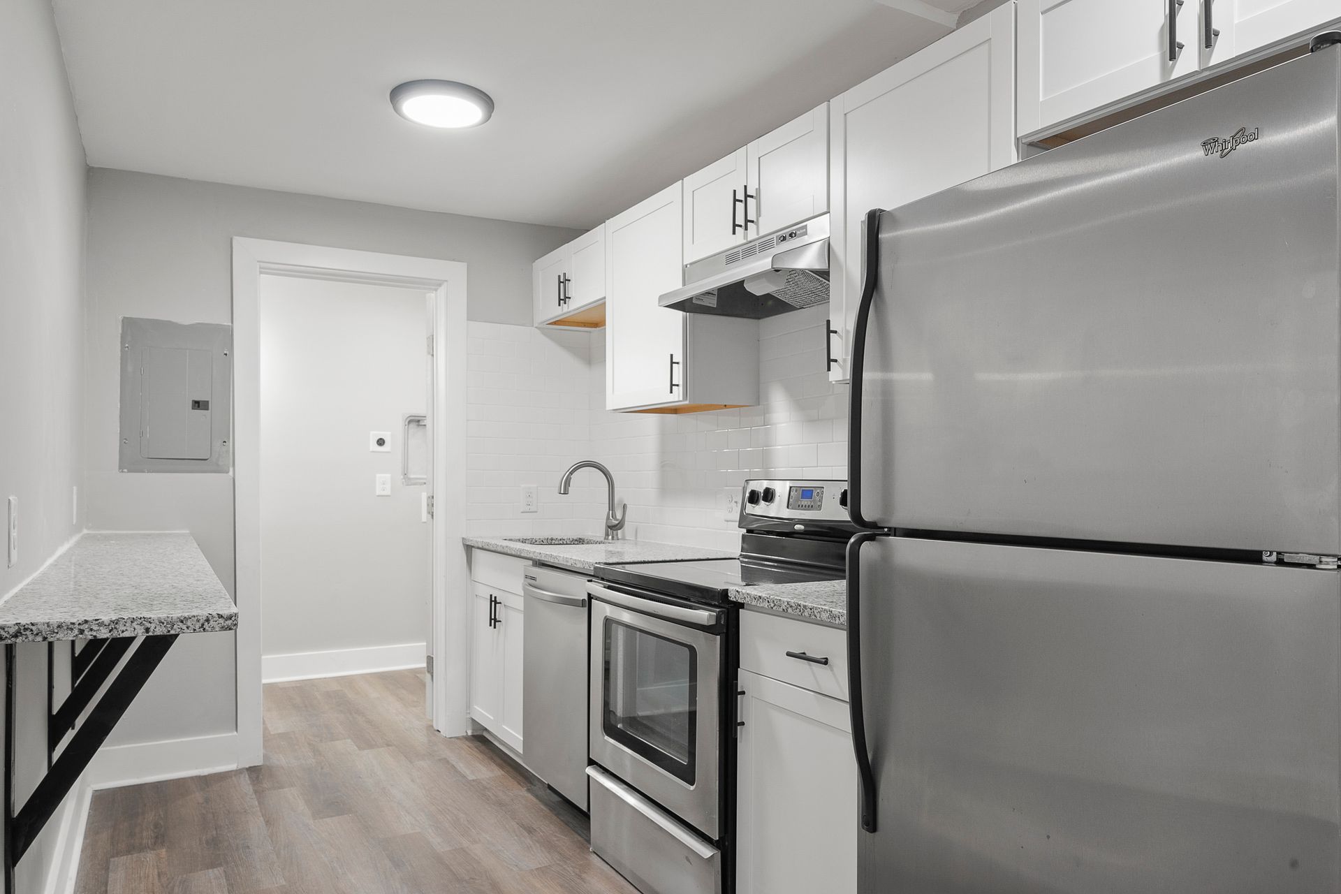 Bright modern kitchen with white cabinets, stainless steel appliances, and light wood flooring.