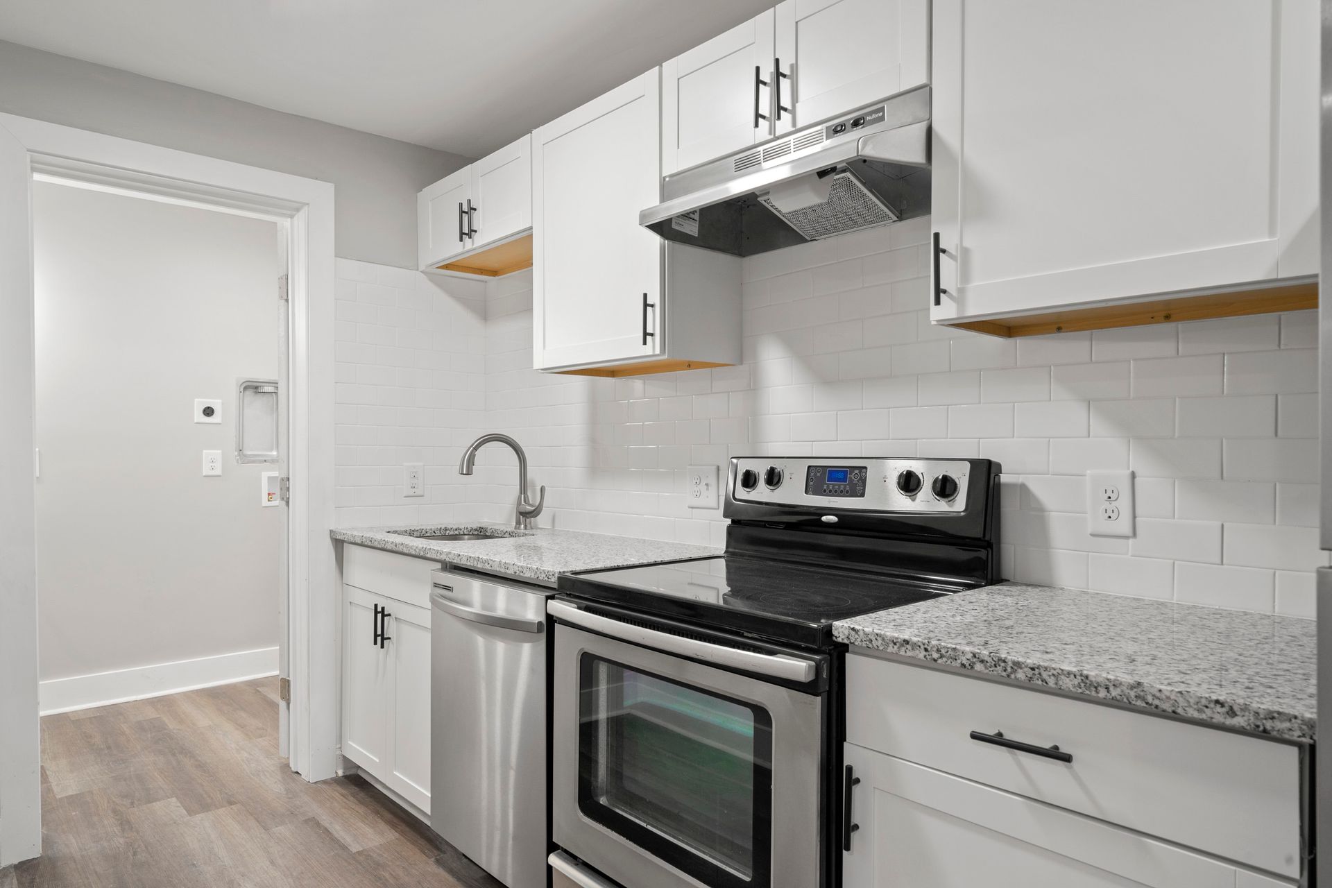 Bright white kitchen with stainless steel stove, granite counters, and white cabinets