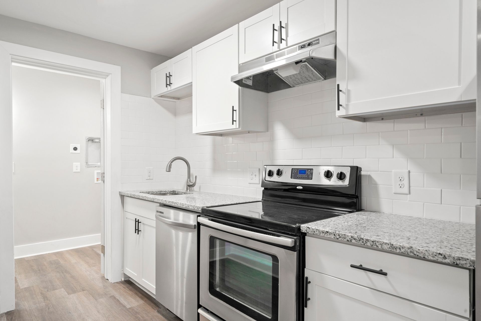 Bright white kitchen with stainless steel stove, granite counters, and white cabinets
