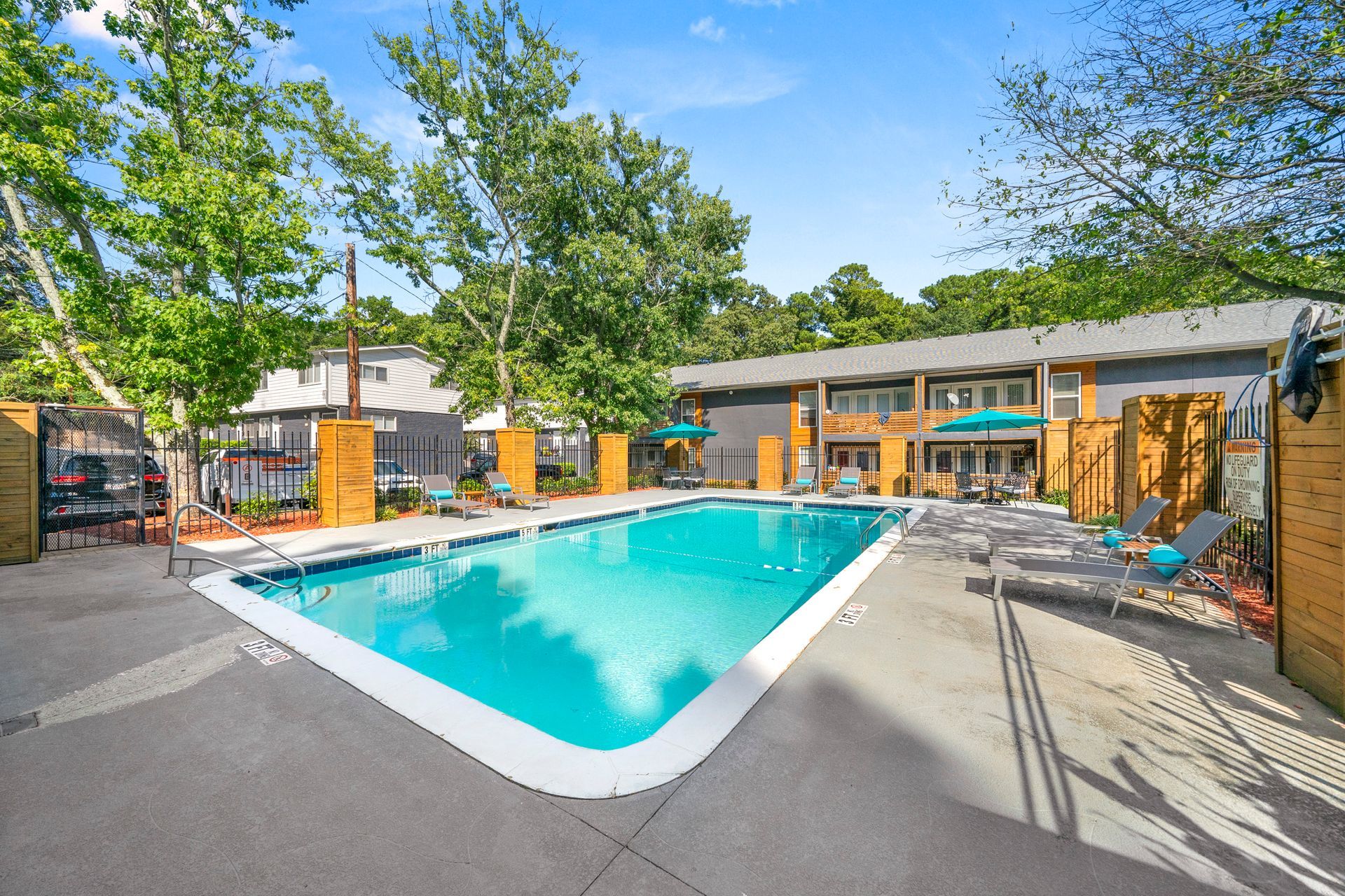 Outdoor swimming pool surrounded by lounge chairs and trees at a motel courtyard