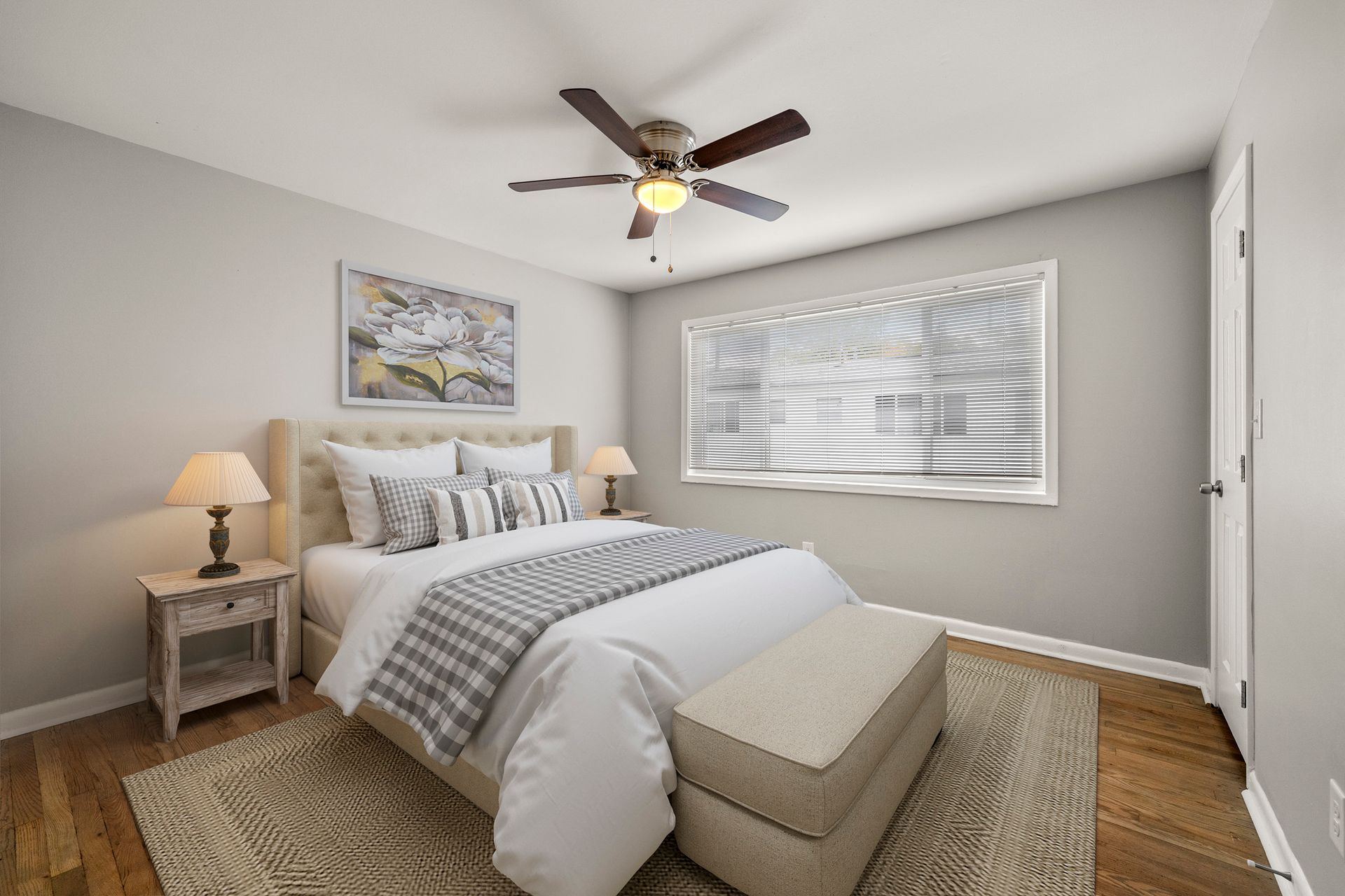 Bright bedroom with a bed, nightstand, ceiling fan, window blinds, and woven rug.
