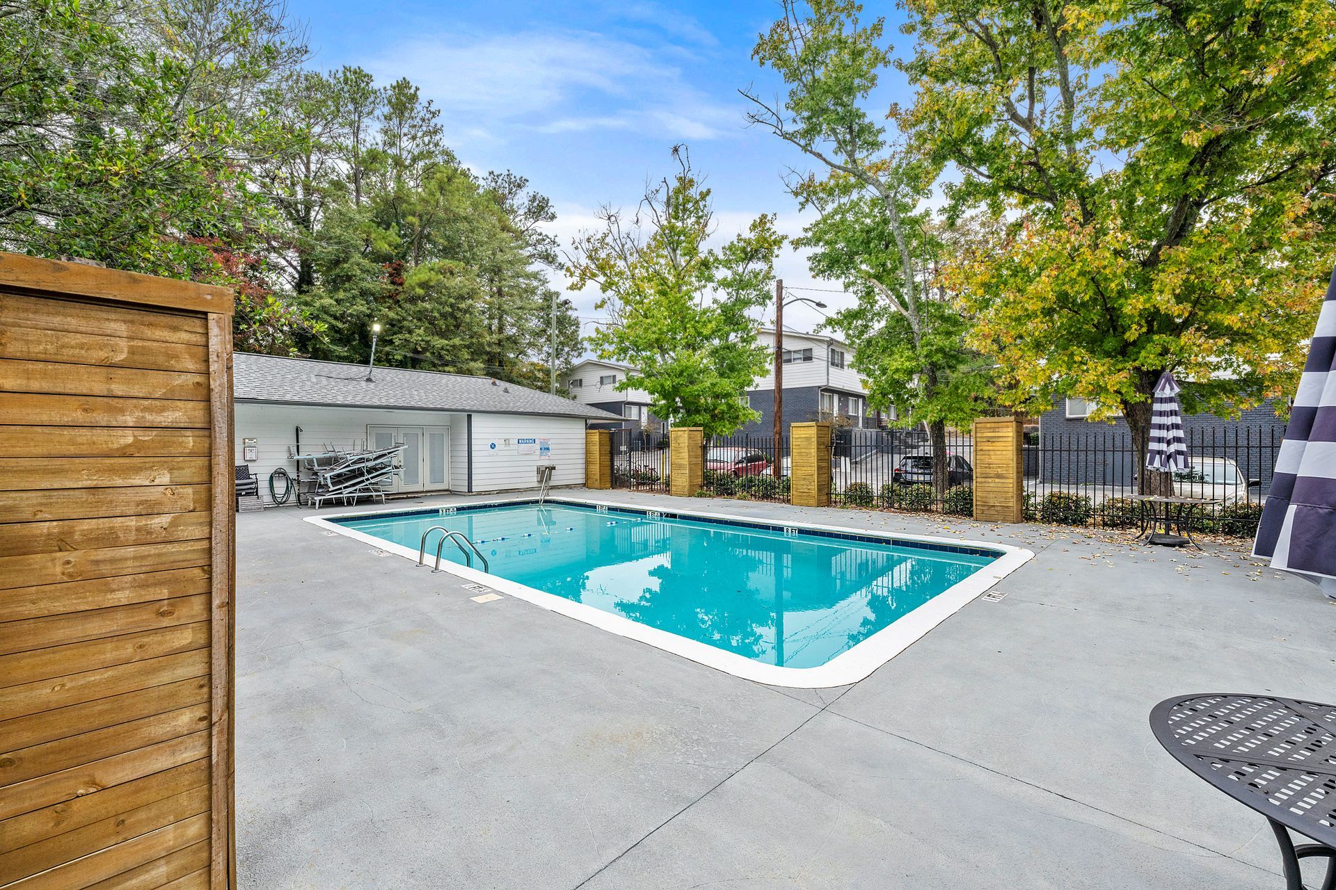 Outdoor swimming pool with turquoise water, concrete deck, and trees in a backyard setting
