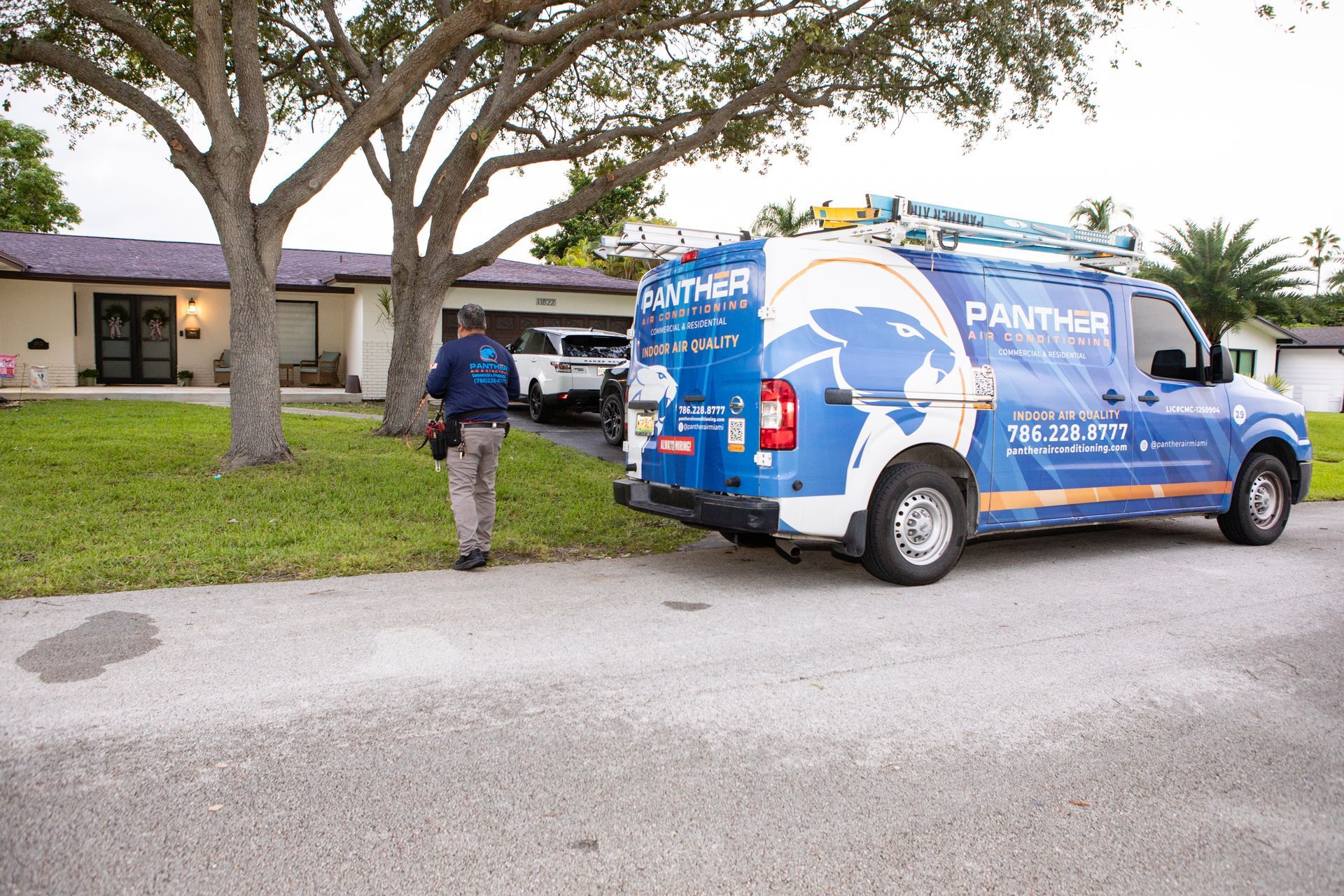 Blue service van parked outside a house, with a worker standing near the driveway.