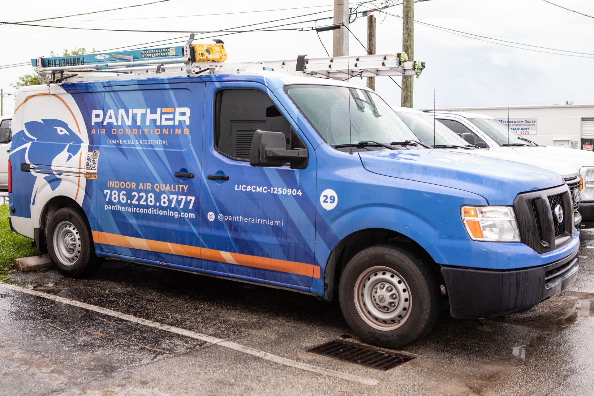 Blue Panther service van parked outdoors in the rain, with ladder racks and company branding.