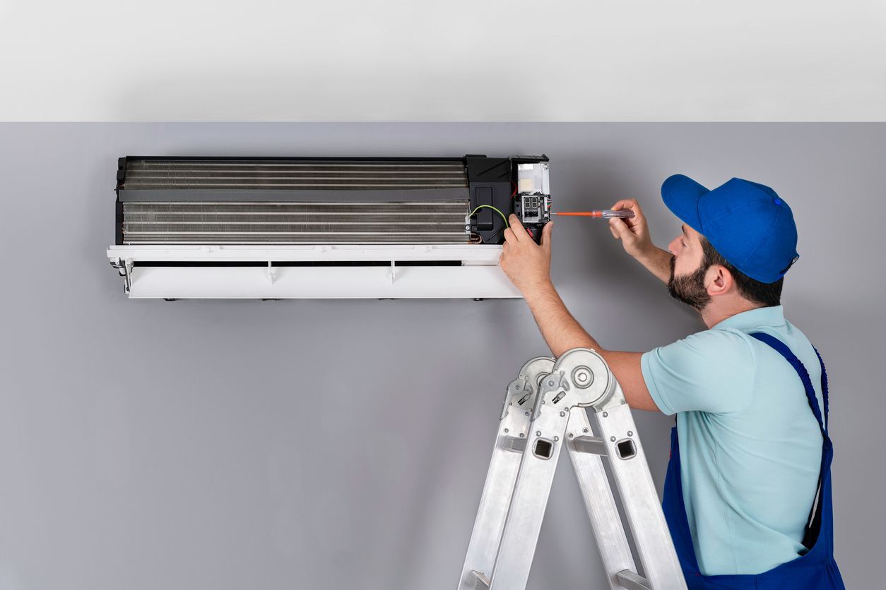 HVAC technician performing residential air conditioner maintenance before summer.