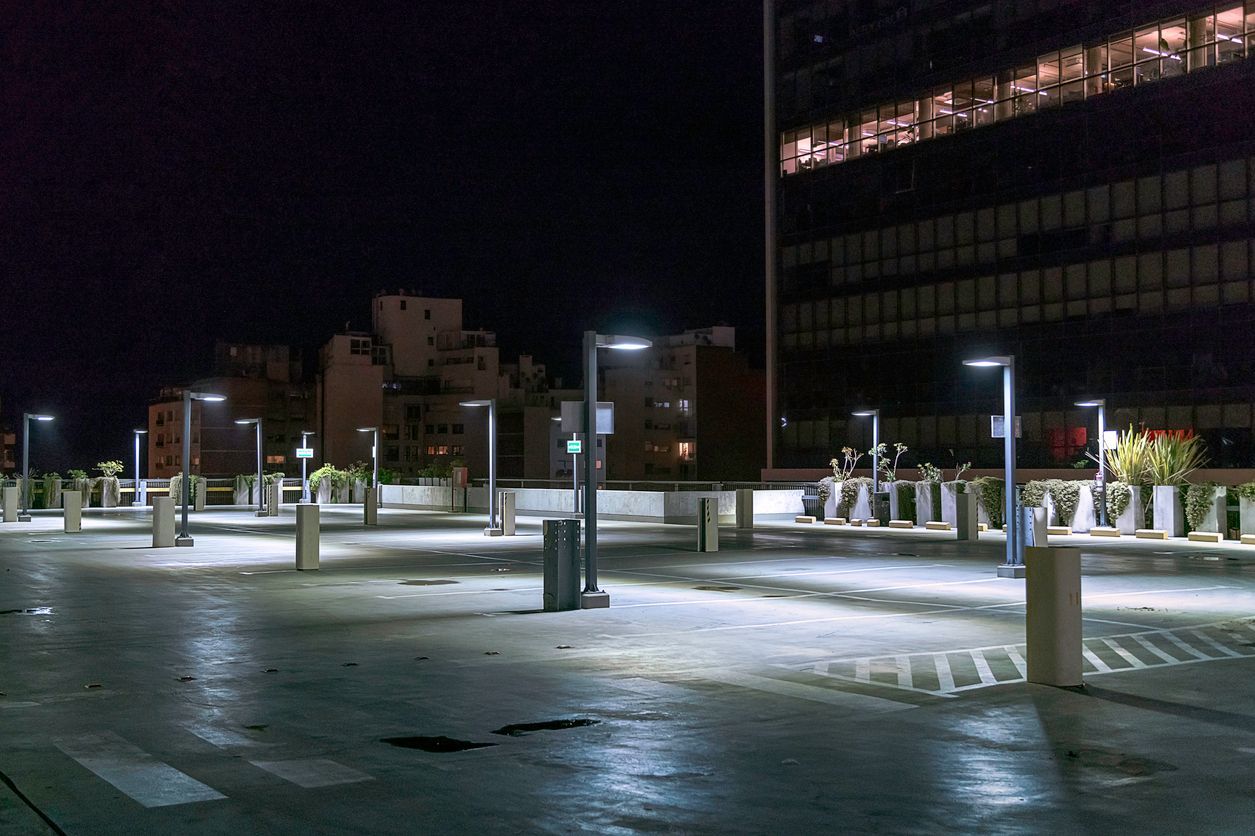 A parking lot is lit up at night with a building in the background.