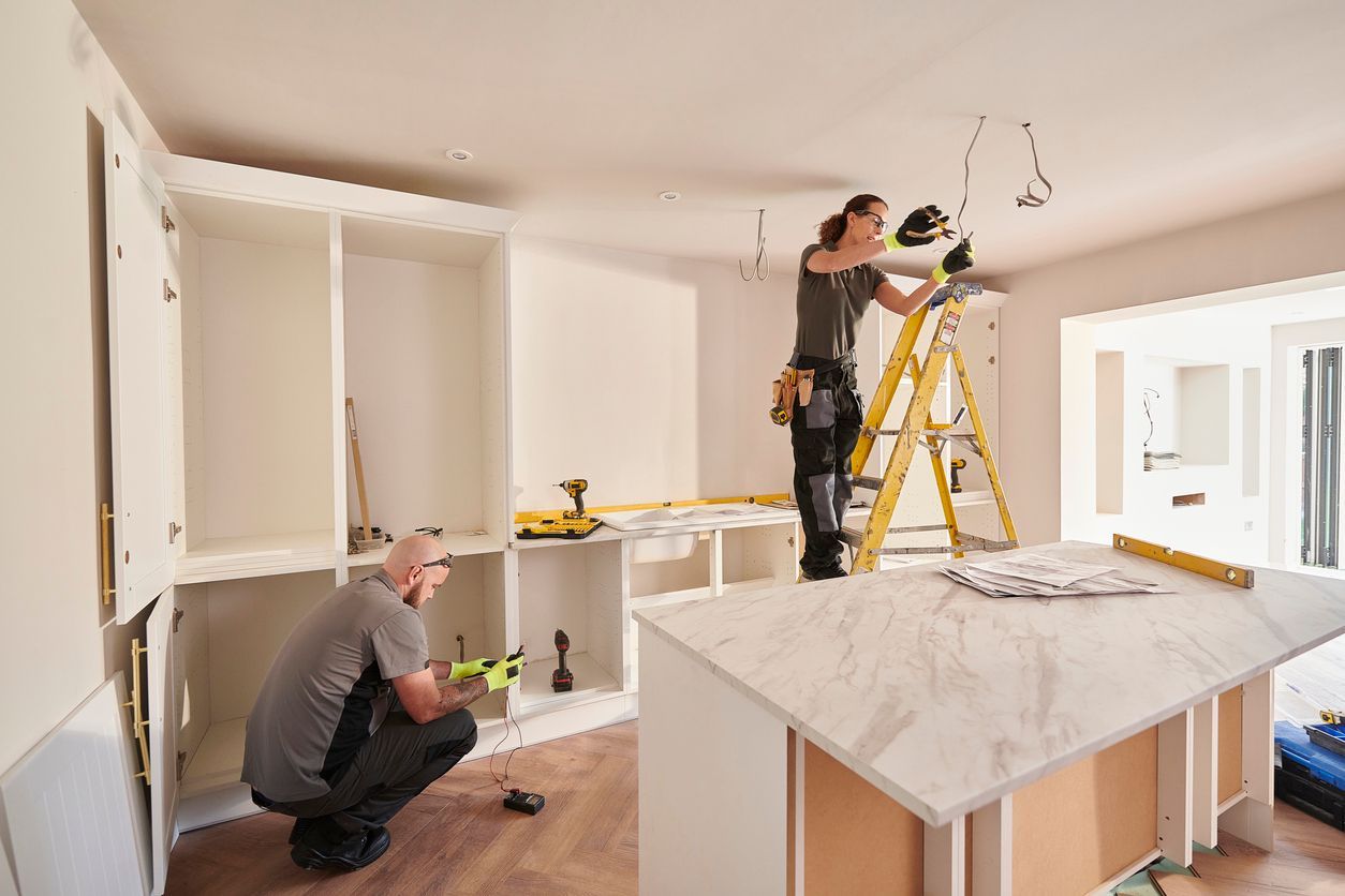 A man and a woman are working on a kitchen.