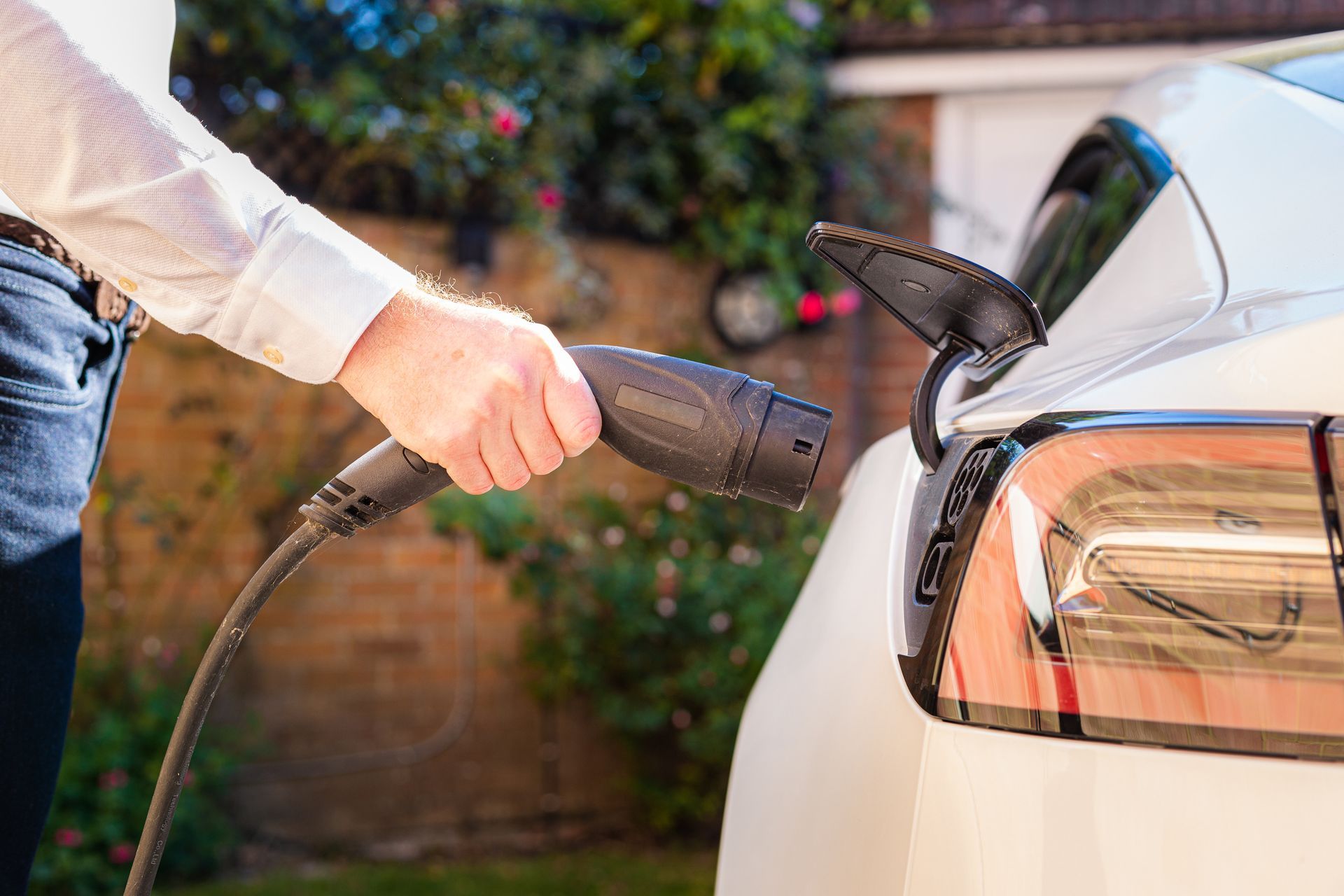 A man is charging an electric car with a charger.