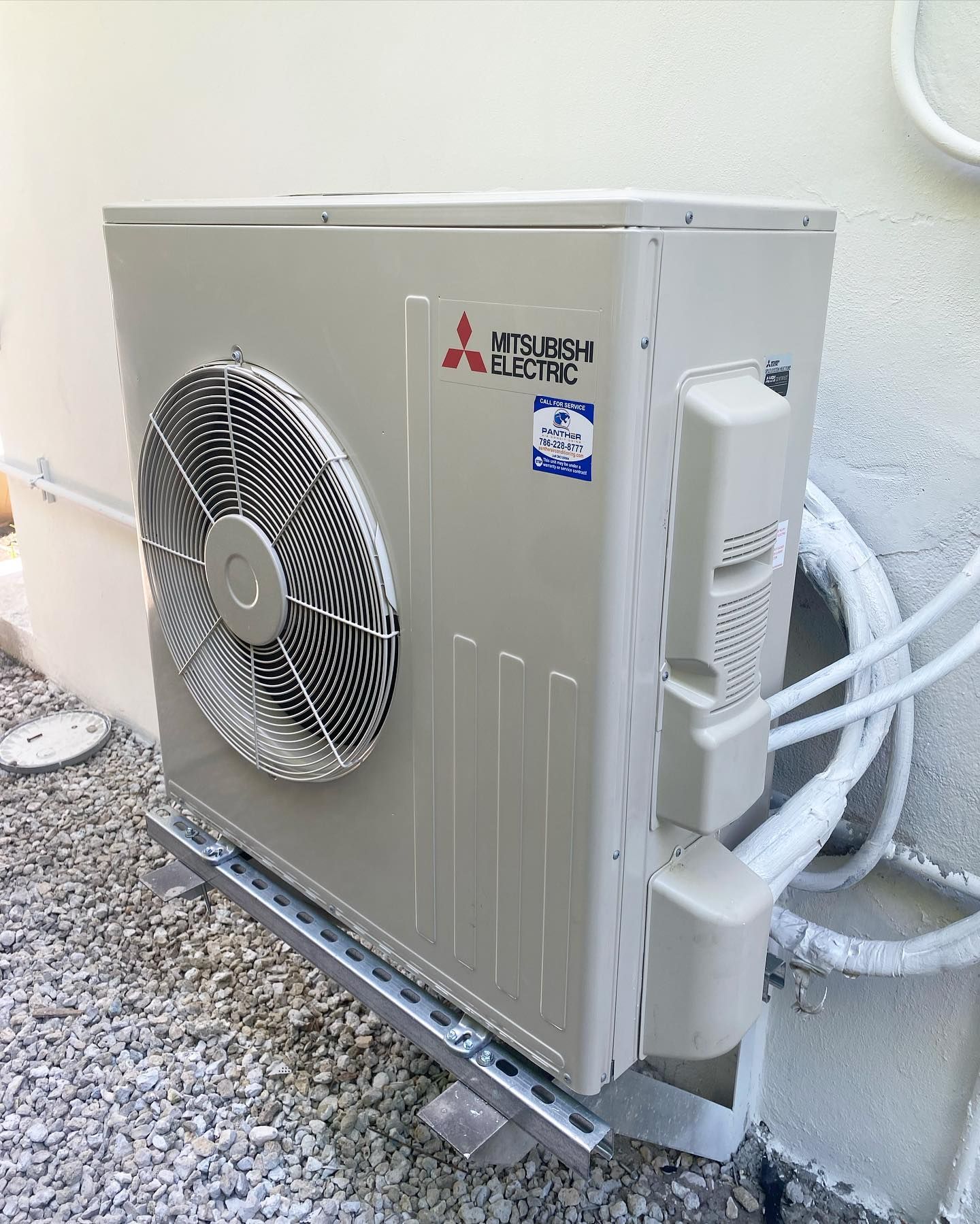 A mitsubishi air conditioner is sitting on the side of a building.