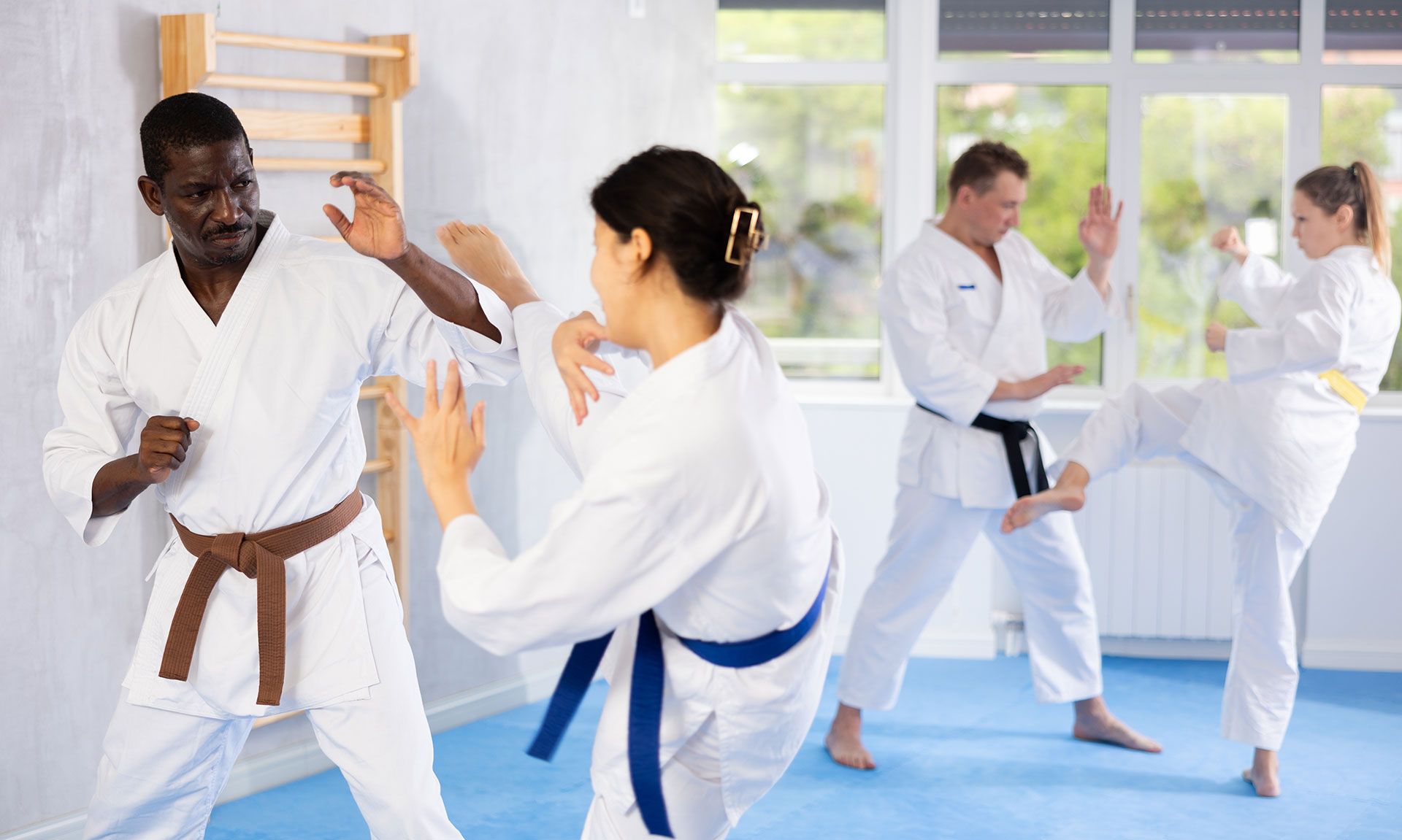 Martial arts class practicing punches and blocks in a bright studio with mats and mirrors