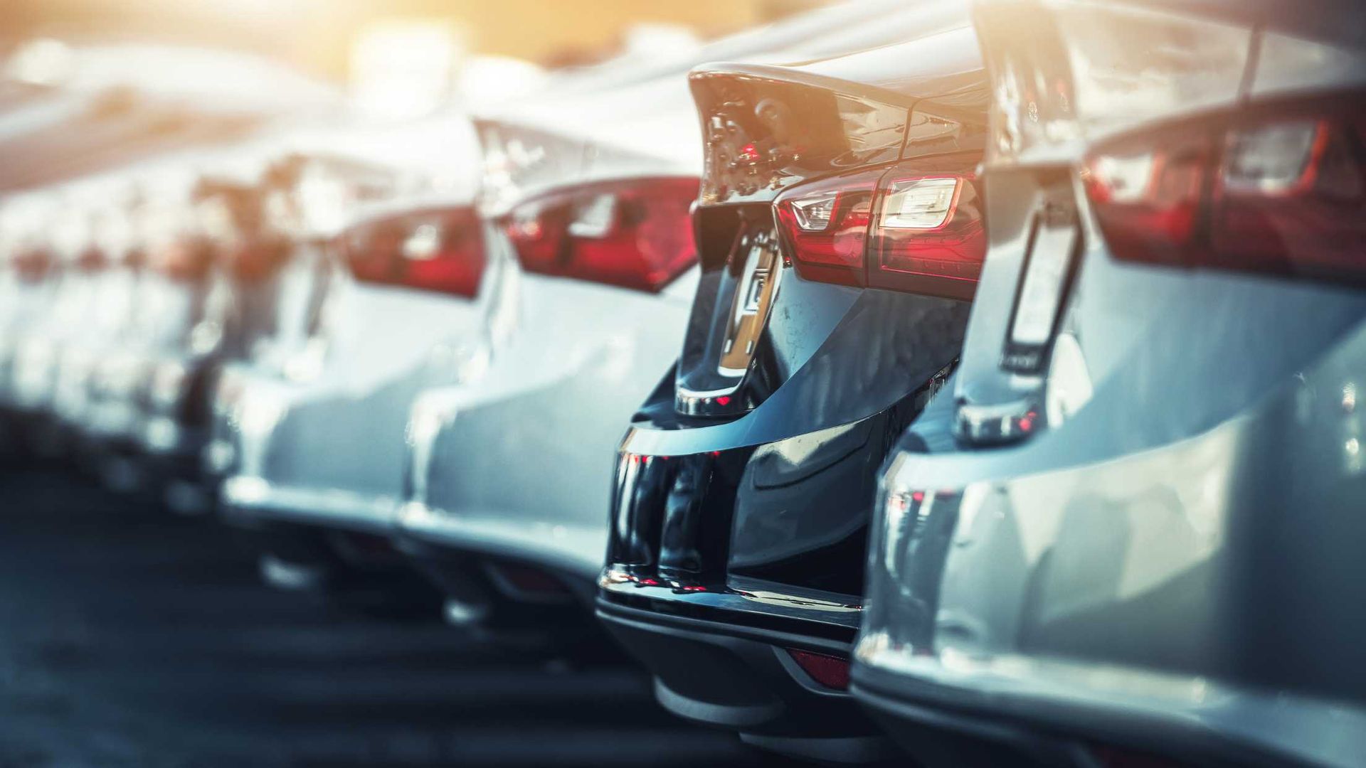 A row of cars are parked next to each other in a parking lot.