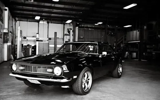 Black classic sports car parked in an industrial garage or workshop | Sparks Tire & Auto