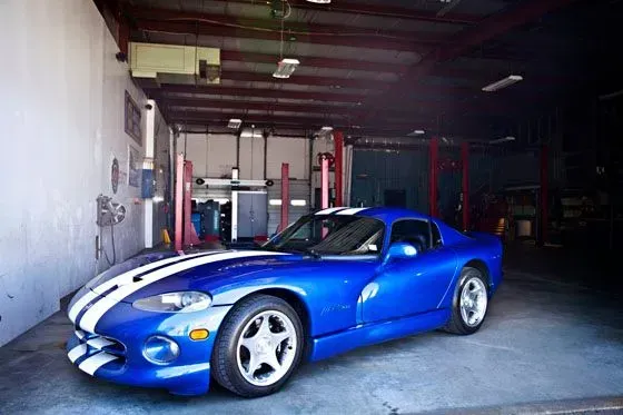 Blue sports car with white racing stripes parked inside a garage | Sparks Tire & Auto